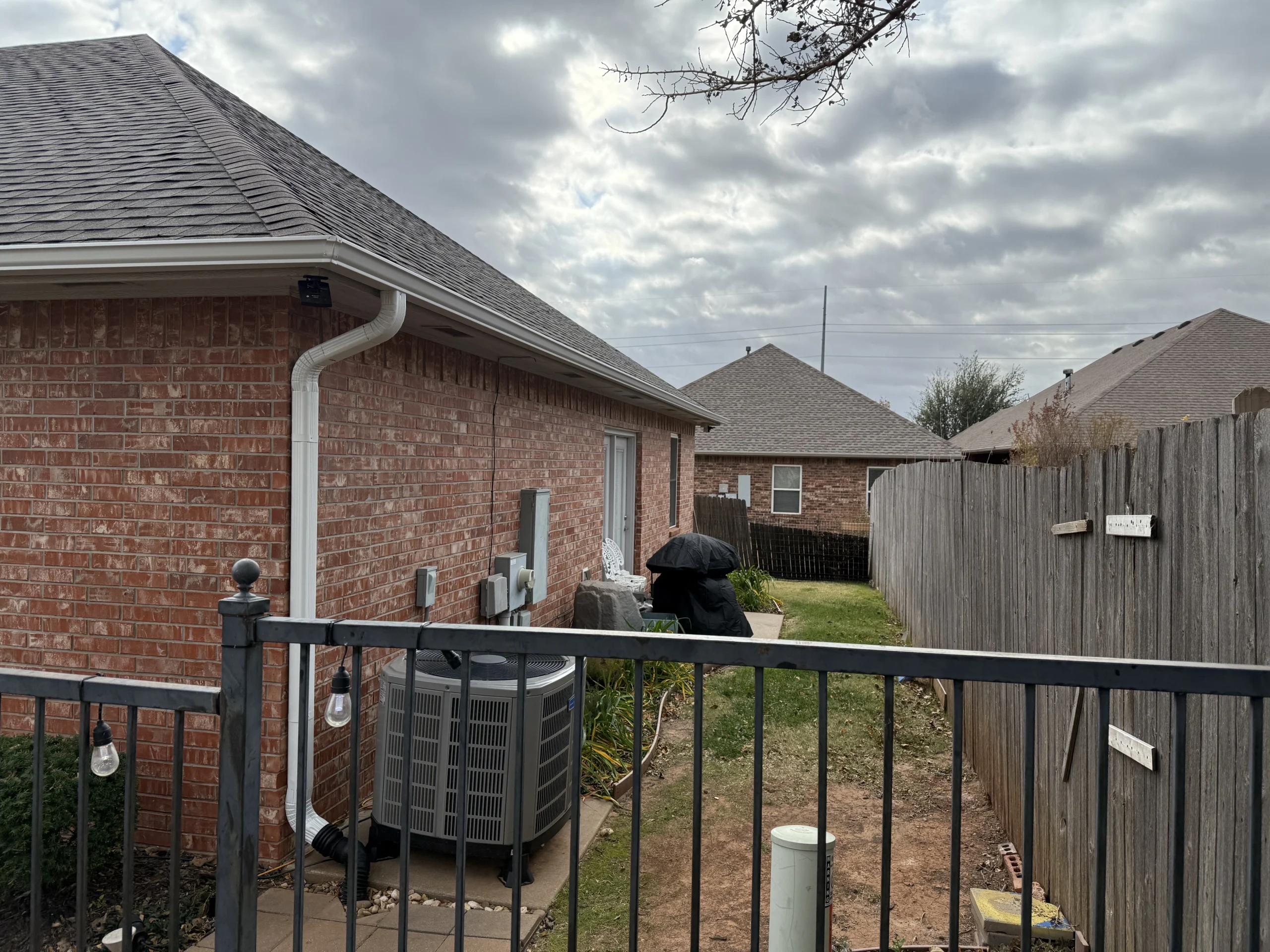 back rear view of a red bricked home with recently installed customer white gutters