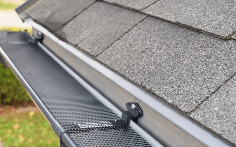 800x450 close up image of a gray roof with silver gutter guards in place