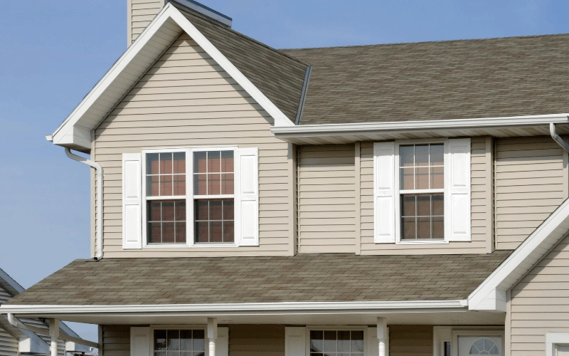 800x450 seamless gutters on a modern two story home with light brown siding and white window shutters