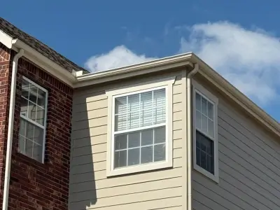commercial gutters on the corner of an apartment complex constructed with  reddish brick and tannish siding